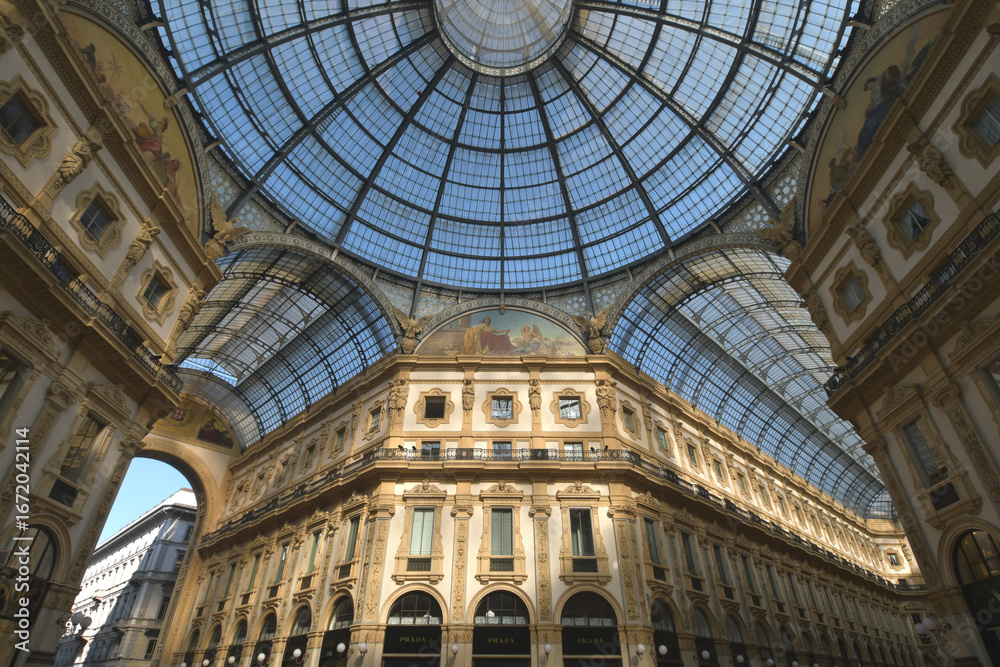 Naklejka premium The Galleria Vittorio Emanuele II is Milan's famous shopping arcade connecting Piazza Duomo to Piazza della Scala. It is renowned for its glass dome, porticoes, and prestigious shops.