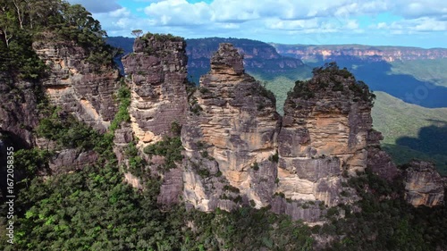 A breathtaking drone shot over Blue Mountains National Park showcases Australia's iconic Three Sisters rock formation and the lush forested valley below.