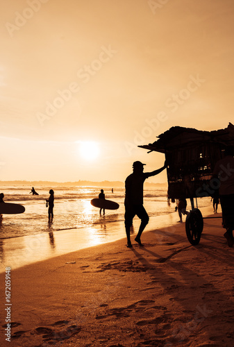 Summer silhouettes of surfers at sunset on the ocean, romantic vacation vibes, tropical beach evening light
