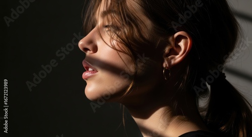 Profile of young caucasian female in dramatic lighting with shadow play