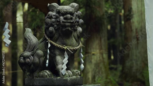 神社の境内にたたずむ狛犬像。森の中に佇む日本の伝統文化の象徴