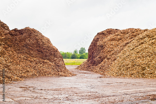 mountains of wood chips against the blue sky and green forest
