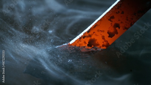 Foto Blacksmith puts the red-hot forged metal part into cold water , close-up