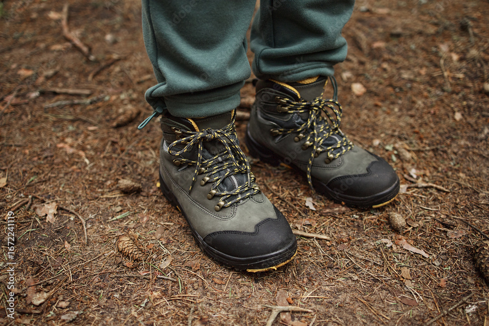 Unrecognizable woman standing on forest ground wearing hiking boots, feet and lower legs visible, laces tied, outdoor setting suggesting trekking or nature exploration Unrecognizable woman standing on forest ground wearing hiking boots, feet and lower legs visible, laces tied, outdoor setting suggesting trekking or nature exploration