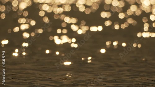 Water Sun Glimmer: Golden sunset reflections on calm water surface, creating bokeh effect.