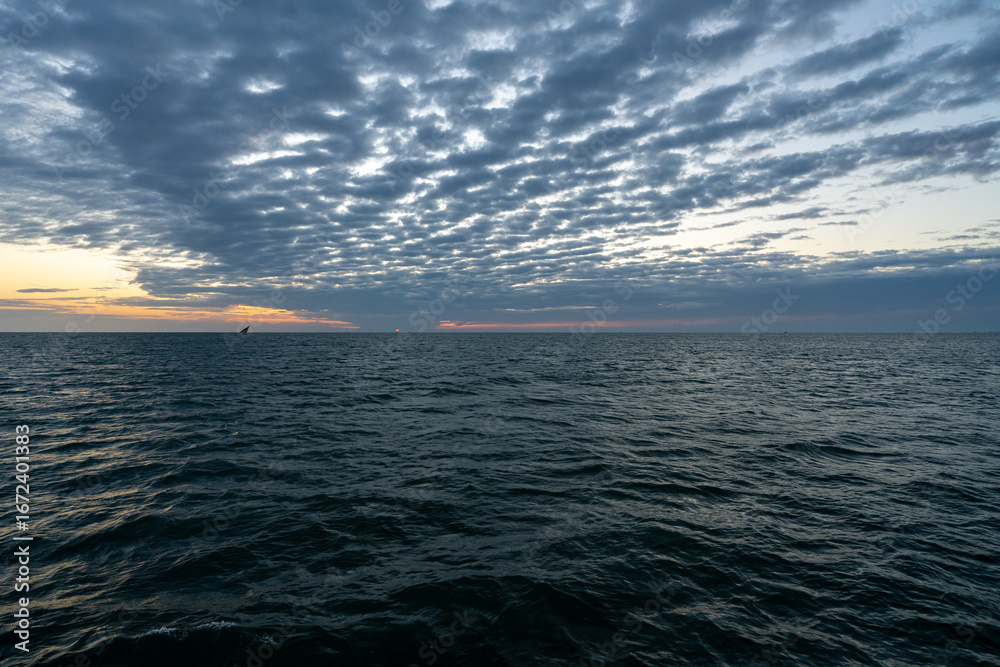 Obraz premium Sunrise view over the Indian Ocean off the coast of Zanzibar, Tanzania, with dramatic clouds stretching across the horizon.