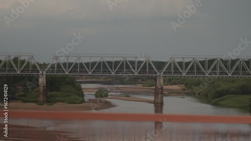 A perfectly tranquil river scene, showcasing a historic bridge alongside sandy riverbanks beneath a soft sky