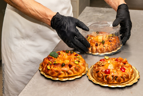 Gloved hands of a chef carefully seal one of three buccellati, traditional Sicilian pastries, into elegant packaging, ready to be enjoyed or gifted.