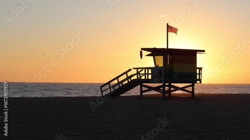 Sunset Silhouette Lifeguard Stand On Ocean With Flag