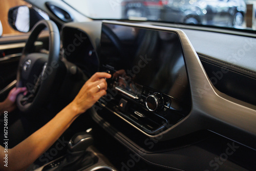 Close-up of a person using a touchscreen in a contemporary car interior, showcasing advanced technology and sleek design.