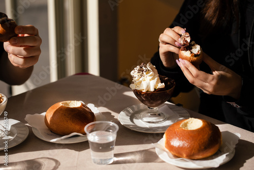 Traditional Sicilian breakfast with granita, whipped cream and brioche. Two people enjoying the sweet treat at a café table, highlighting Italian culture and culinary tradition.