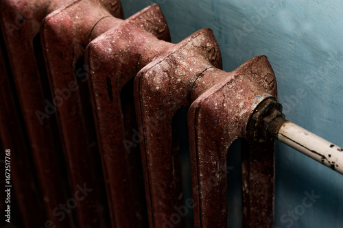 Close-Up of Rusty Radiator with Chipped Paint Against Blue Wall