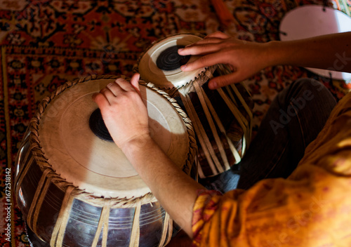 Musician Playing Traditional Indian Tabla Drums Indoors on Ornate Carpet