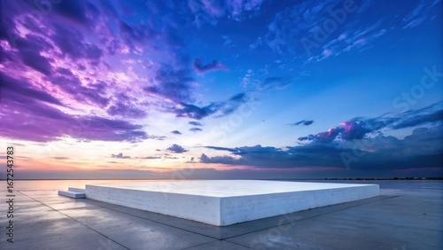 Fototapeta Naklejka Na Ścianę i Meble -  Empty white podium platform on a wet reflective surface against a dramatic purple and blue sunset sky with clouds