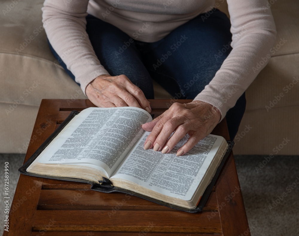 Fototapeta premium Elderly Woman's Hand Pointing to Bible Verse