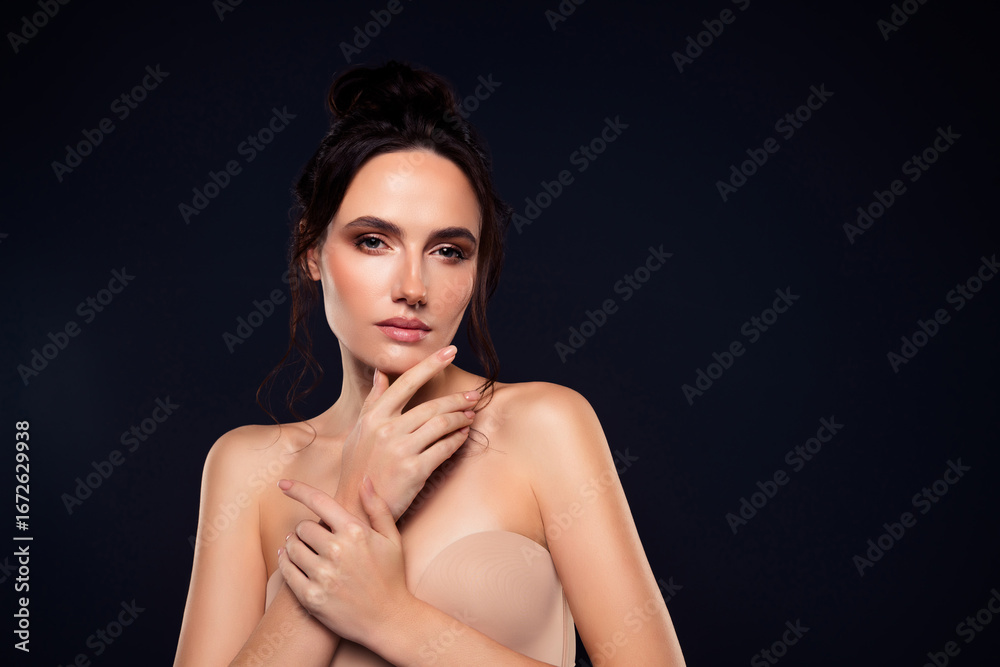 Fototapeta premium Beautiful young woman with natural makeup and brown hair posing against a dark background