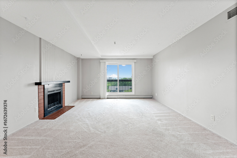 Obraz premium Large, empty living room with a fireplace and a window