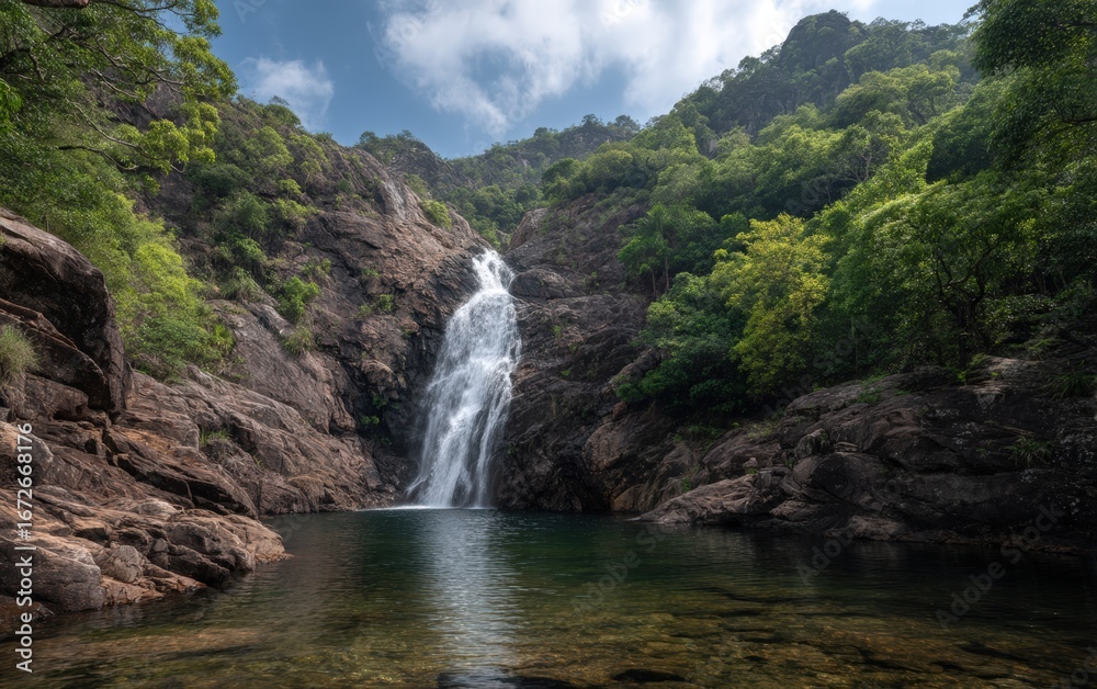 Fototapeta premium Majestic waterfall flowing into clear lagoon surrounded by jungle, captured in vibrant daylight for nature conservation and wildlife tourism.