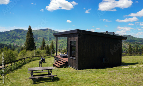 Black wooden cabin and outdoor furniture with mountain view