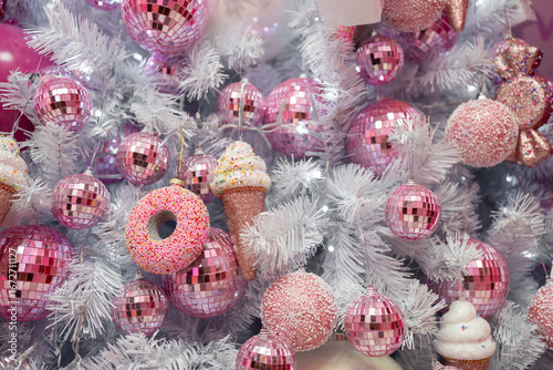 Closeup of beautiful white Christmas tree decorated with pink shiny balls and ice creams. Festive holiday concept, showcasing a unique and playful decoration