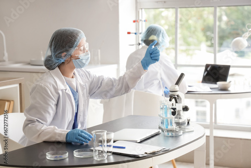 Female scientist working with Petri dish at table in laboratory