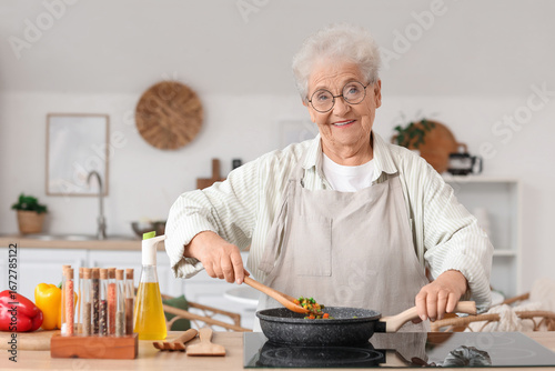 Senior woman frying vegetab...
