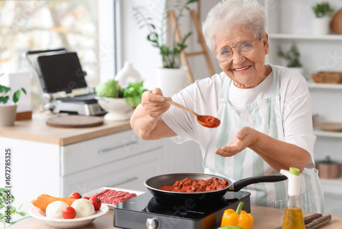 Senior woman frying food in...