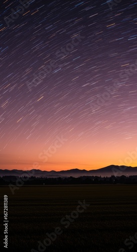 Star trails over a landscape at dawn