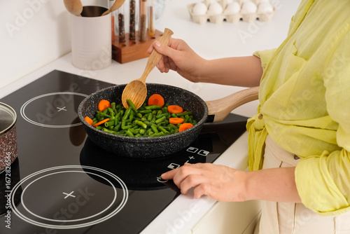 Woman with spoon frying veg...