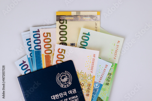 Stack of South Korean won banknotes arranged with dark Korean passport, showcasing currency identity together.