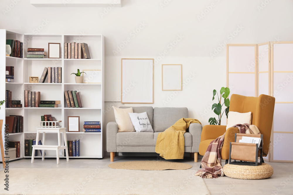 Fototapeta premium Interior of stylish living room with brown armchair, grey sofa and bookshelf