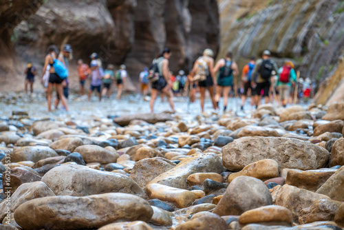 Tablou pe pânză Hikers explore the rocky riverbed of a breathtaking canyon on a sunny day filled