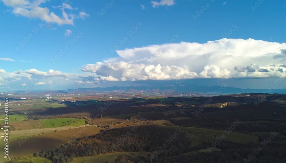 Naklejka premium Vast Landscape Under a Dramatic Sky with a Large Cloud Formation.