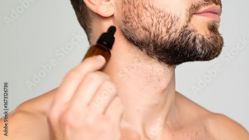 Man applying oil to beard with dropper bottle