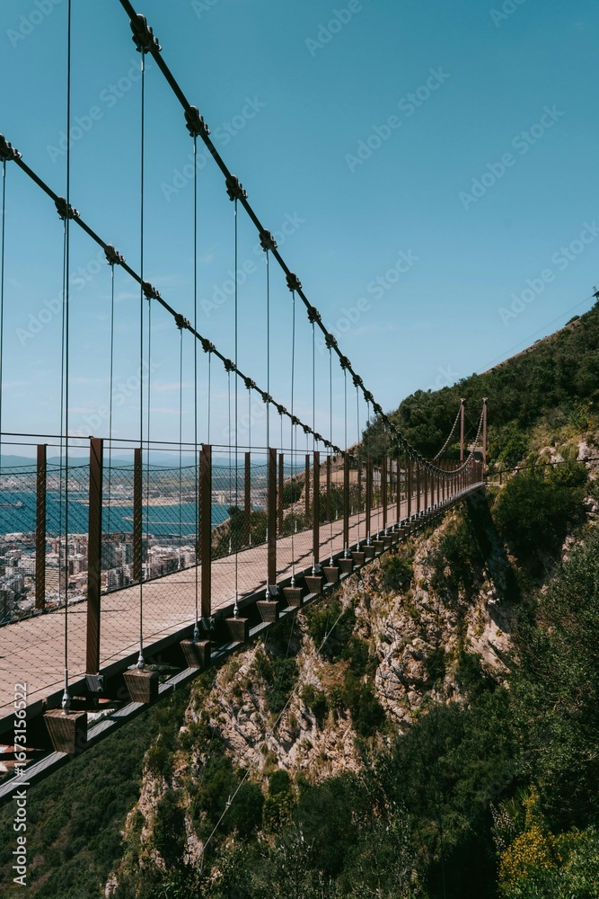 Fototapeta premium Suspension bridge over the river in the mountains with scenic landscape and water view