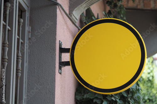 Fotografi Bright yellow circular sign mounted on a building wall