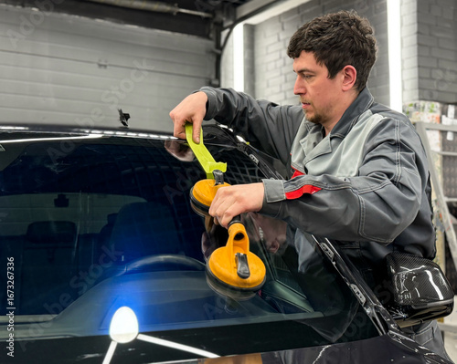 Bild auf Leinwand Automobile special workers replacing windscreen or windshield of a car in auto service station garage
