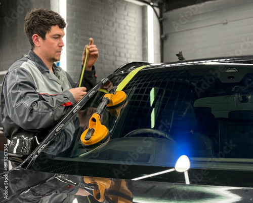 Foto Automobile special workers replacing windscreen or windshield of a car in auto service station garage
