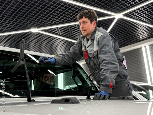 Foto Automobile special workers replacing windscreen or windshield of a car in auto service station garage