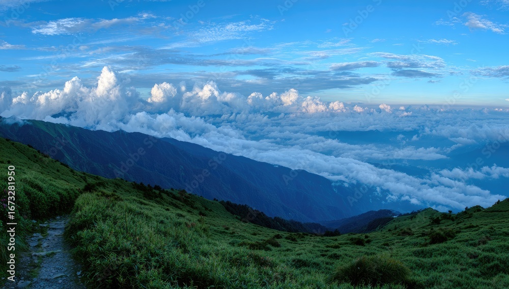 Fototapeta premium Lush mountain vista with rolling clouds hugging peaks under a blue sky