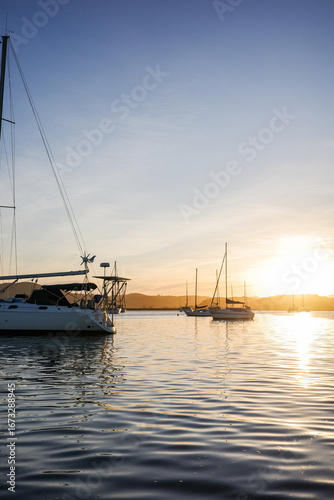 Peaceful sailboats anchored on calm waters during a golden sunset. A scenic seascape capturing the beauty of sailing, leisure travel, and tranquil evenings on the ocean in Knysna, Garden Route