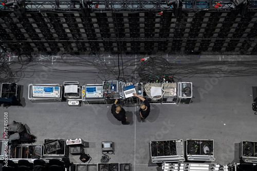 Aerial view of production crew operating control equipment and monitors during concert setup