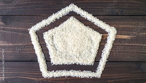Rice grains forming abstract pentagon shape on dark wood