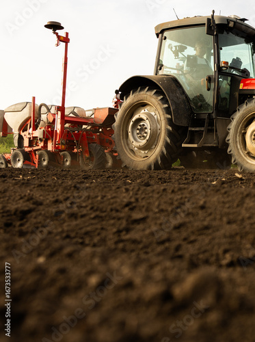 Farmer with tractor seeding in sunset