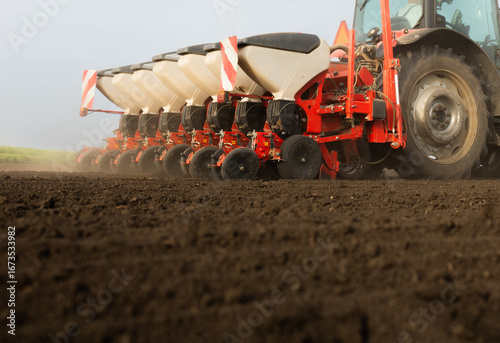 Farmer with tractor seeding in sunset