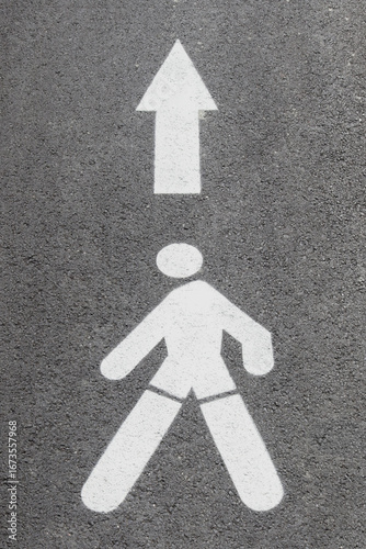 Horizontal road sign: pedestrian figure and an arrow on the asphalt.
