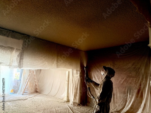 Construction worker applying spray foam insulation on ceiling during renovation project