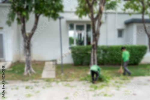 Blur the background of two gardener man sweeping leaves by broom sweeps