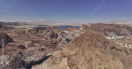 Hoover Dam Nevada Aerial v2 flyover the desert terrain capturing freeway bridge spanning the Black Canyon, with Lake Mead in the background under clear sky - Shot with Mavic 3 Pro Cine - Apr 16th 2024