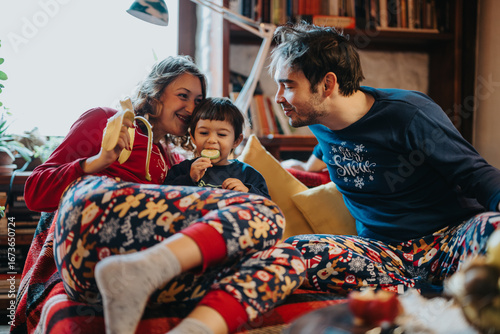 Slika na platnu Warm and joyful family bonding shared in a festive ambiance, complete with playful pajamas and holiday cheer
